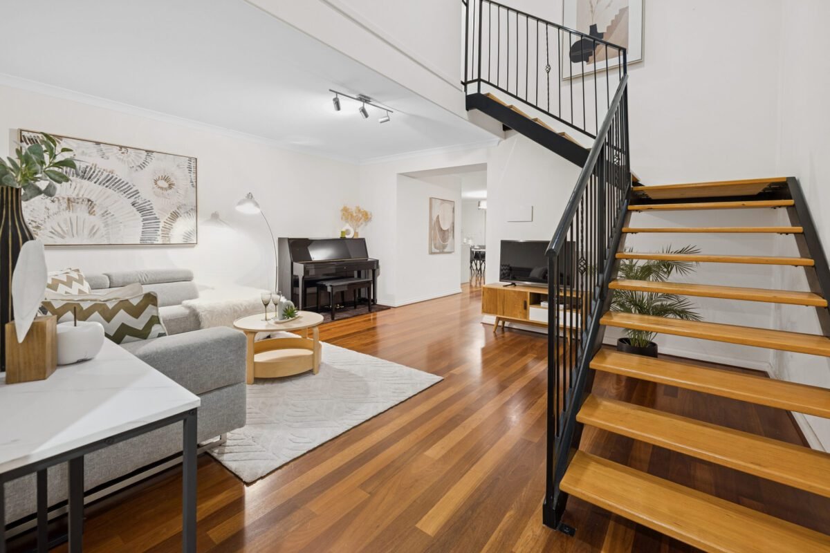 Modern open-plan living room with timber floors, stylish furniture and staircase, showcased by Gregory Swiatek - Ray White Real Estate